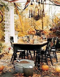 an outdoor dining area with pumpkins and leaves on the ground