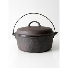 an old iron pot with a lid on a white surface