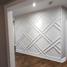 an empty room with white walls and wood flooring in the center is a large cabinet that has geometric designs on it