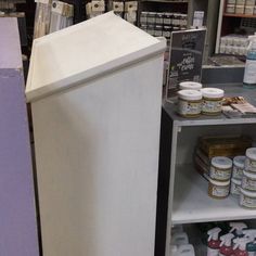 an empty refrigerator in a store next to shelves with jars and other items on it