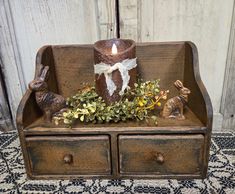 a candle is sitting on top of an old wooden box with some plants and bunnies