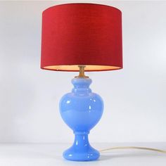 a blue table lamp sitting on top of a white counter next to a red shade