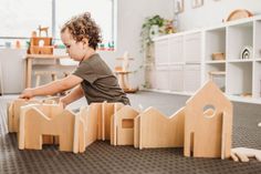 a young child playing with wooden toys in a playroom