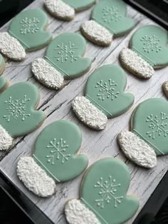 cookies decorated with frosting in the shape of heart and snowflakes on a tray