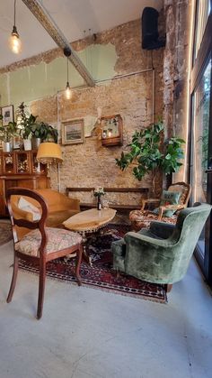 a living room filled with furniture next to a brick wall covered in pictures and plants