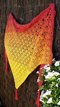 an orange and yellow shawl next to white flowers