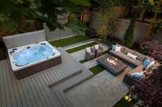 a hot tub sitting on top of a wooden deck next to a fire pit in a backyard