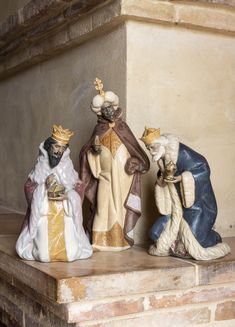 three figurines sitting on top of a stone shelf next to each other in front of a brick wall