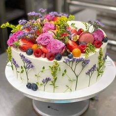 a white cake topped with fresh fruit and flowers