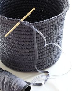 a basket with yarn and knitting needles next to it on a white surface, ready to be sewn