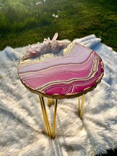 a pink and gold table sitting on top of a white rug next to a green field