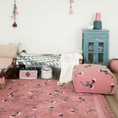 a bedroom with pink rugs and furniture in front of a white wall, including a bed