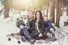 a man, woman and two children sitting in the snow