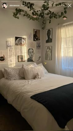 a bed with white sheets and pillows in a bedroom next to a window filled with pictures