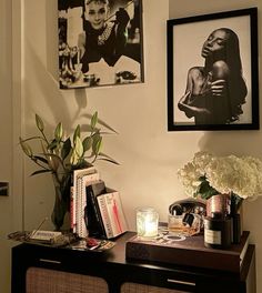 a black and white photo hangs on the wall next to a table with flowers, candles and books