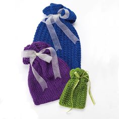 two knitted hats with bows on them sitting next to each other, one blue and one green