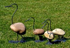 three metal birds sitting on top of green grass