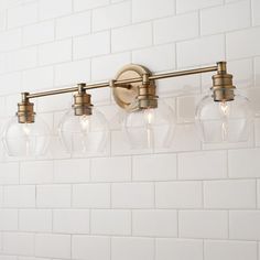 a bathroom light fixture with five clear glass globes on the bottom and gold metal arms