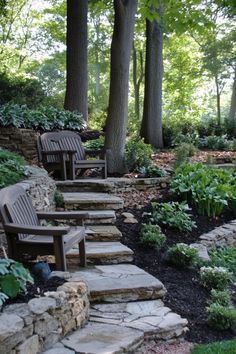 Stone steps leading up through a lush garden with wooden chairs and trees in the background. Forest Backyard Landscapes, Forest Yard Landscape, Woodsy Backyard, Gravel Front Yard Landscaping, Montana Landscaping Ideas, Corner Landscaping Ideas, Forest Landscaping, Wooded Backyard Ideas, Woods Backyard Ideas