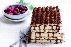 a chocolate cake with bananas and raspberries in the middle next to a bowl of berries