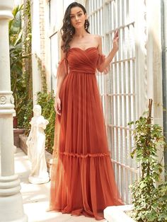 a woman in an orange dress posing for the camera with her hand on her hip