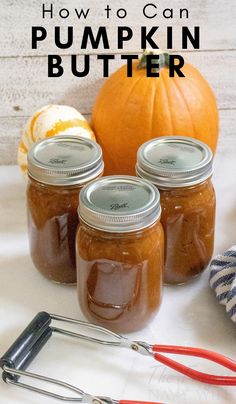 three jars filled with pumpkin butter sitting on top of a table next to a whisk