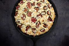 a pizza in a cast iron skillet with almonds and figs on top