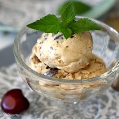 an ice cream sundae in a glass bowl with a green leaf on top