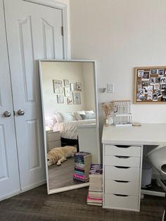 a mirror sitting on top of a wooden floor next to a white desk and chair