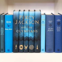 a row of blue books sitting on top of a white book shelf next to each other