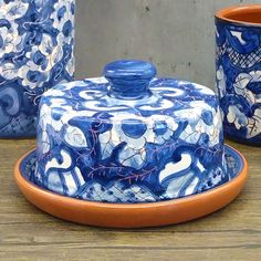 three blue and white dishes sitting on top of a wooden table next to each other