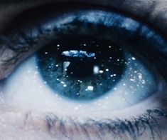 an eye with the reflection of stars in it