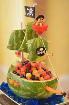 a watermelon boat filled with lots of fruit and pirate flags on top of it