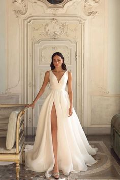 a woman in a white dress standing next to a chair