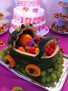 a watermelon boat filled with lots of fruit on top of a purple table