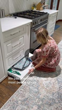 a woman kneeling down in front of an open oven