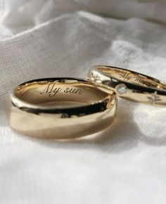 two gold wedding rings with the words my sun on them sitting on a white cloth