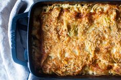 a casserole dish with cheese and broccoli in it on a white cloth