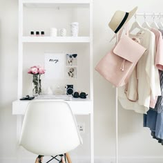 a white desk and chair in front of a shelf with clothes on it, shoes hanging up