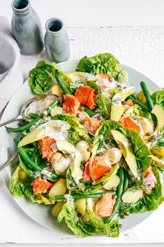 a salad with salmon and green beans on a white plate, ready to be eaten