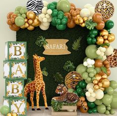 an animal themed baby shower with balloons and jungle animals on the wall, including giraffes