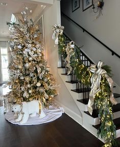 a decorated christmas tree sitting in the middle of a living room next to a staircase