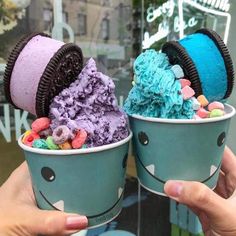 two ice cream cones with colorful toppings in their hands, one is blue and the other is purple