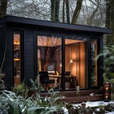 a small black cabin in the woods is lit up