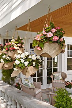 three hanging baskets filled with pink and white flowers on top of a wooden porch railing