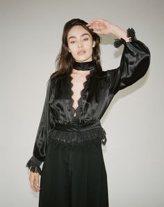 Our Rita Blouse in black features a plunging V neckline trimmed with delicate Venise lace, a true waistline cinch and soft billowing sleeves all trimmed with Alençon lace and embroidered ruffled tulle lace. 100% Silk Charmeuse lined with Silk Habutai Three satin covered pearl buttons for each closure Dry clean only Each piece is made to order and handcrafted in our atelier. Slight variations may occur as each piece is unique. Night Out Lace Blouse With Lace Collar, Evening Long Sleeve Lace Top With Lace Trim, Evening Lace Top With Long Sleeves And Lace Trim, Long Sleeve Lace Top For Date Night, Black Lace Trim V-neck Top, V-neck Lace Trim Top For Night Out, V-neck Lace Top With Lace Trim For Night Out, Evening V-neck Blouse With Ruffles, Lace V-neck Top For Evening