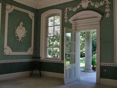 an empty room with green walls and white trim on the doors, windows and columns