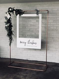 a sign that says merry christmas hanging on a wall next to a potted plant