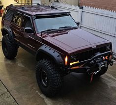 a red jeep parked in front of a white fence