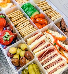 a tray filled with lots of different types of food next to crackers and strawberries